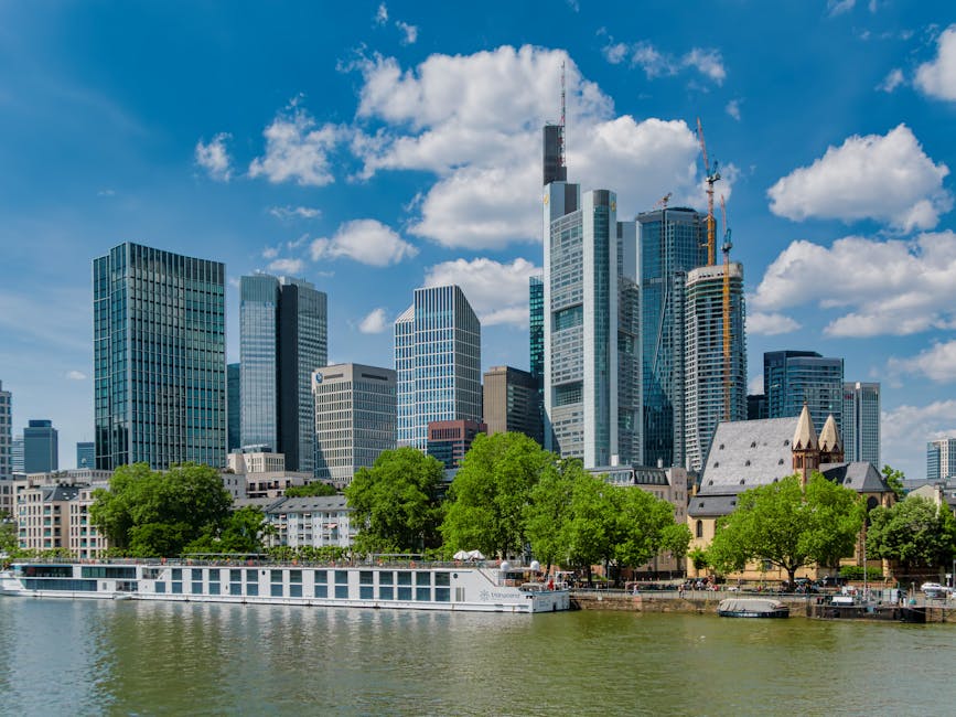Stunning view of Frankfurt's skyline from the river with modern skyscrapers under a bright blue sky.
