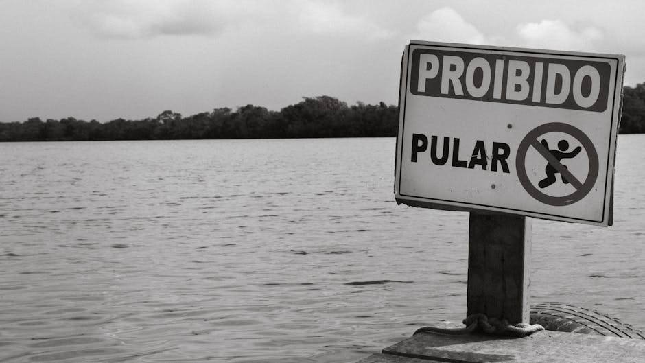 A black and white photo of a no jumping sign by the water in Sergipe, Brazil.
