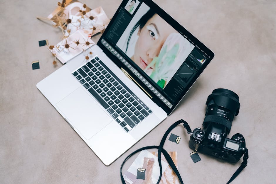 Flat lay of a laptop with photo editing software, camera, and memory cards on a desk.