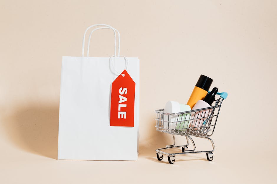 White shopping bag with red sale tag and mini shopping cart on beige background